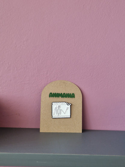 A black and white skeleton & bat pin with 'there it goes, my last flying fuck' written above & underneath it. Pin is mounted on a brown cardboard backing with the brand Animania written above it.