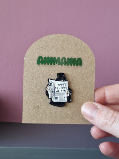 Jack the ripper pin that says 'ripper strikes again' on a newspaper. Pin is mounted on a brown cardboard backing with the brand Animania written above it.